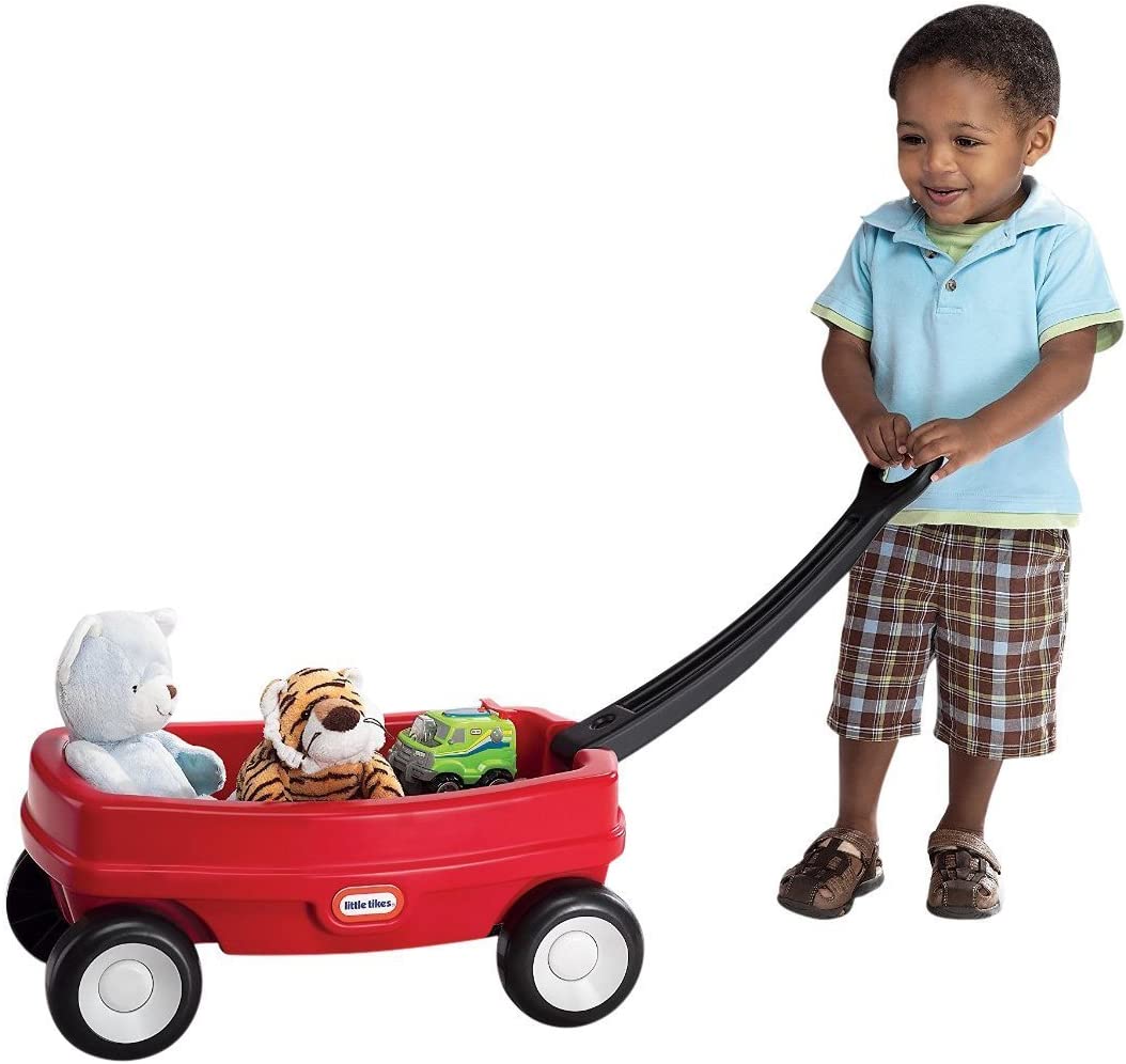 Toddler pulling a red kids wagon loaded with stuffed animals and toys